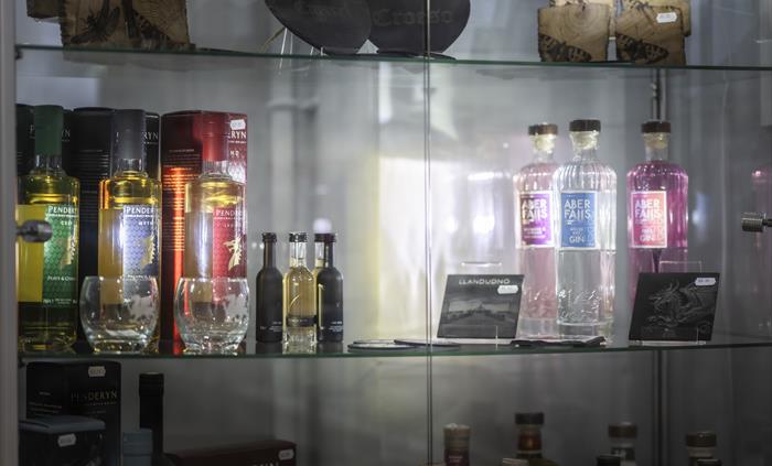 Glass display cabinet featuring Welsh spirits, Penderyn whisky, local gin and artisan gifts from North Wales producers.